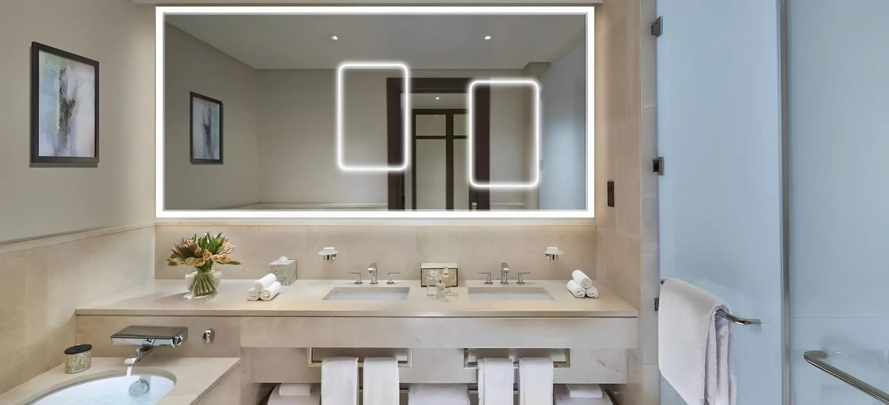 A clean bathroom featuring a modern sink and a large mirror reflecting the bright, well-lit space.