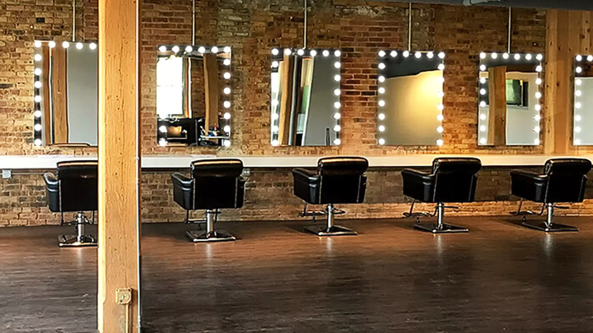 Rustic salon, where mirrors and luminous lights grace the walls, casting a mesmerizing glow of elegance and allure.