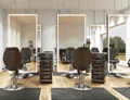 Compact of ceiling-hung illuminated mirrors with black chairs in a beauty salon.