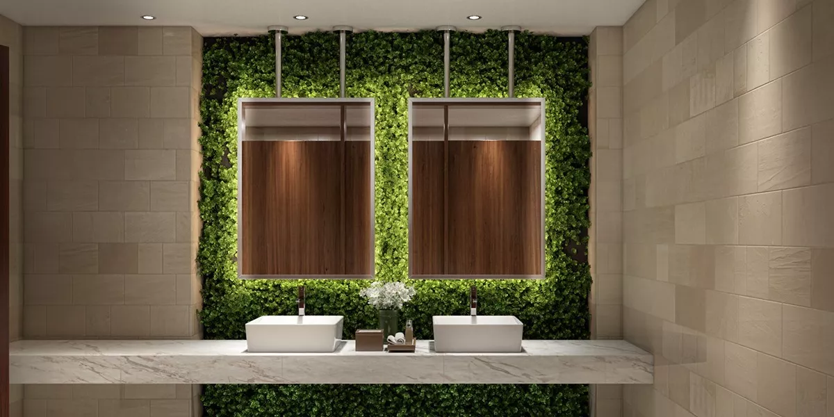 Two stainless steel ceiling-mounted mirrors with green grass wall and two sinks.