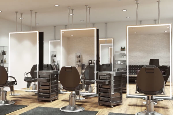 Full-length ceiling-mounted lit mirrors with black chairs and a salon trolley cart.