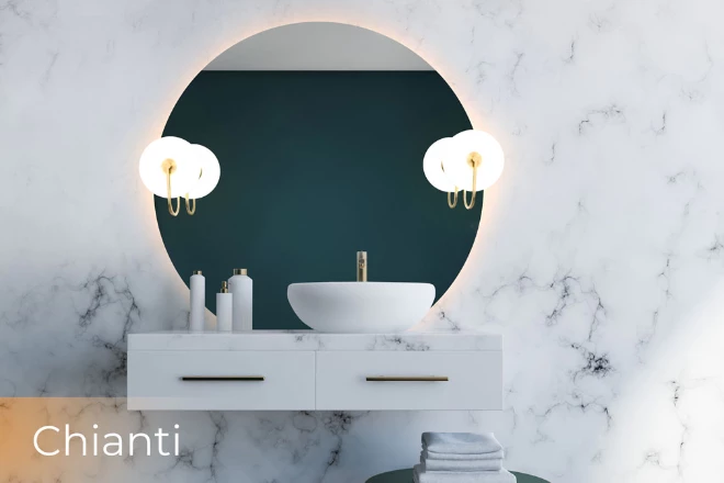 A circular-backlit mirror with Chianti lamp on a white marble wall above a cabinet sink.