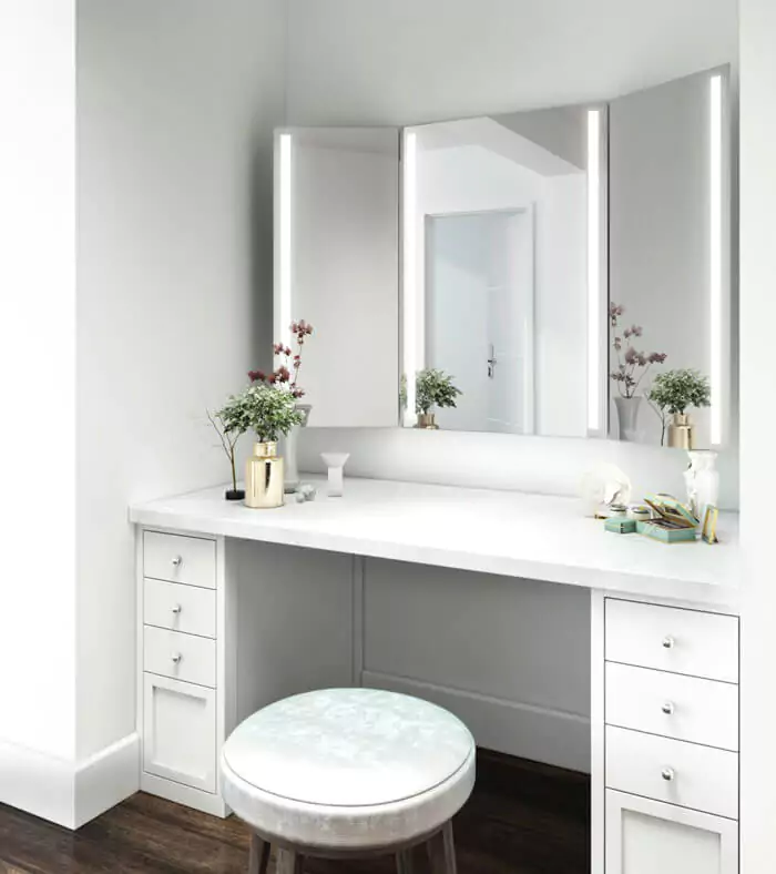 Trifold lighted mirror installed on a white wall above a cabinet with vanity stool.