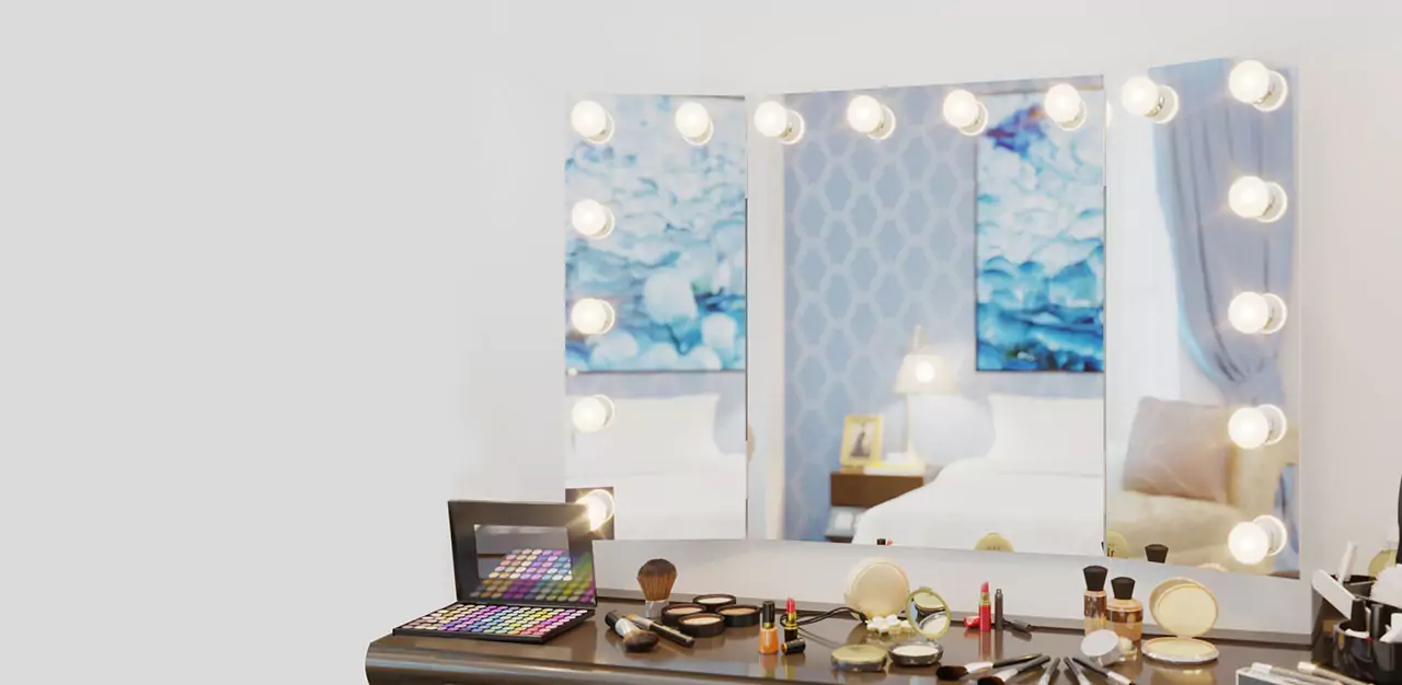 A trifold Hollywood mirror is mounted on the wall above a table of makeup essentials.