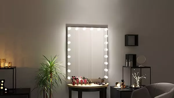 Compact of Hollywood mirror mounted on the wall with make-up accessories on a vanity table.