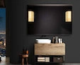 A small of frameless mirror with a Mascioni lamp set in a black wall above a bathroom cabinet.