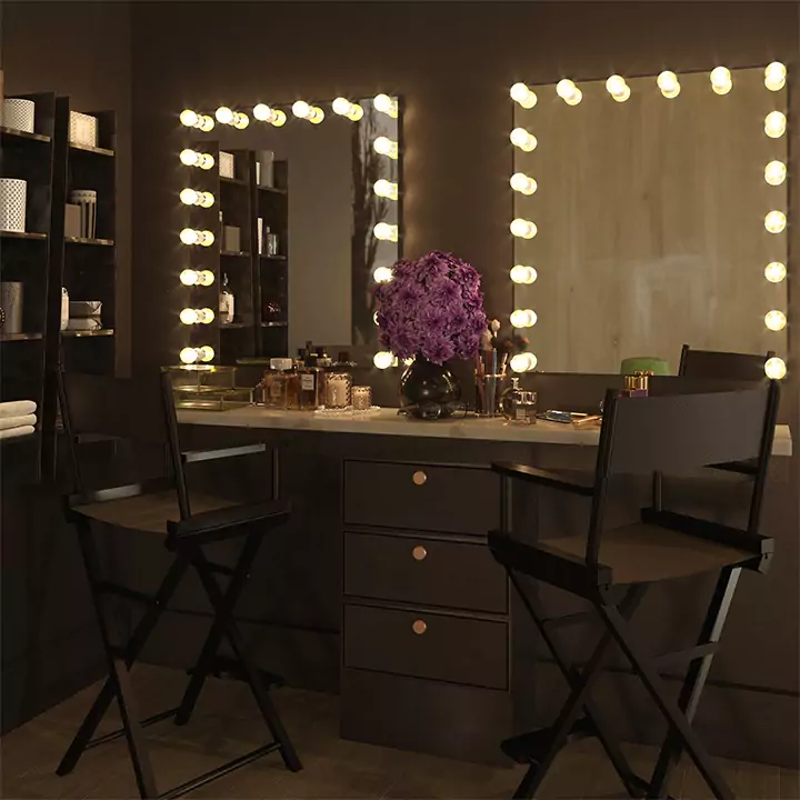 Two Hollywood mirrors above a vanity cabinet with two canvas folding chairs.