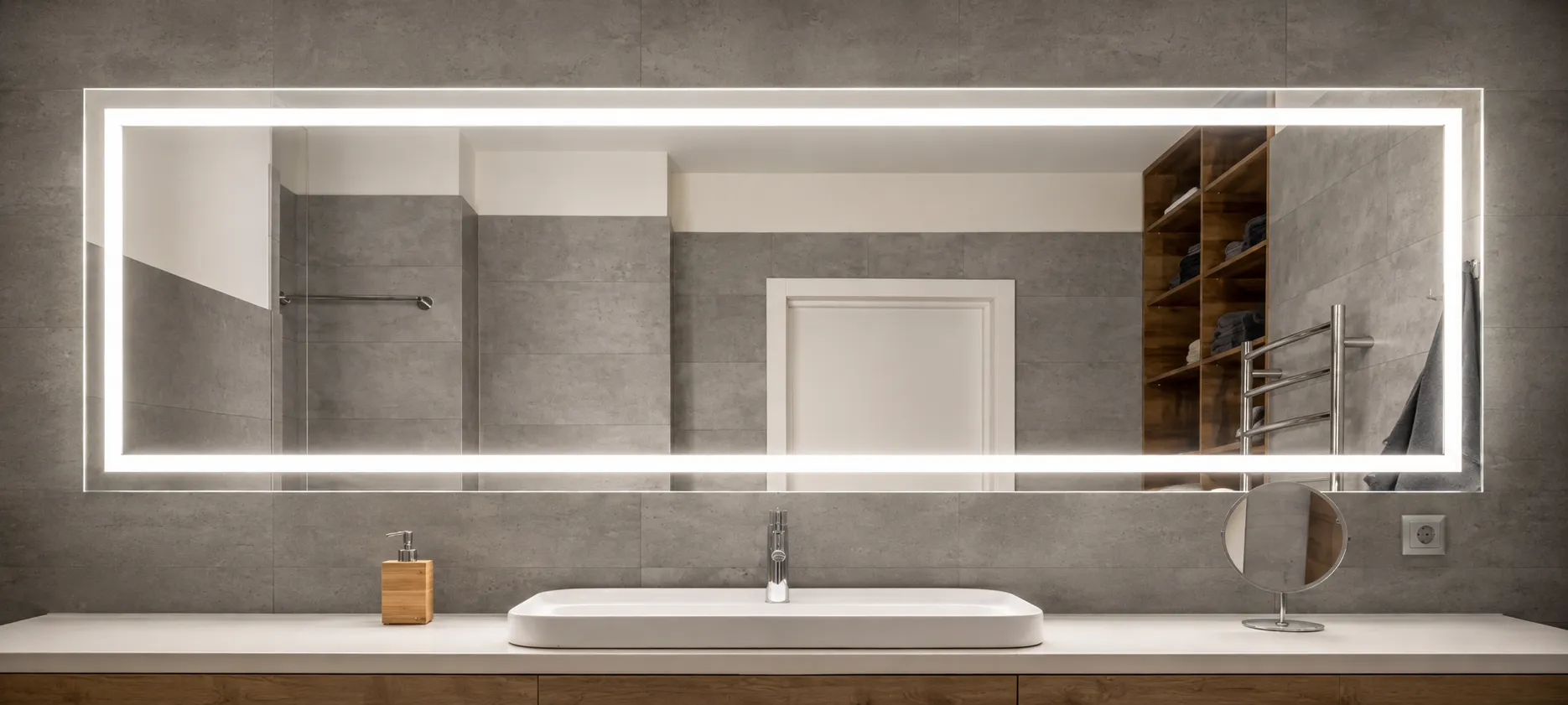 Custom frosted mirror mounted on a blue mosaic tiled wall and bathroom essentials below in Dubai.