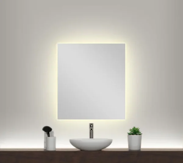 A warm backlit mirror on a white wall above a single sink on a wooden countertop.