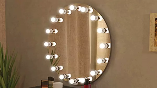 Snippet of a circular Hollywood mirror mounted on a brown wall.