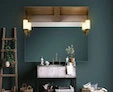 A mini-tachini lamp in a mirror set into a wall with a plant ladder on the side of a basin.